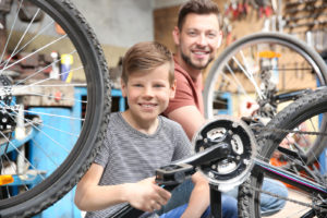 A father and son preparing a bicycle for bike storage.